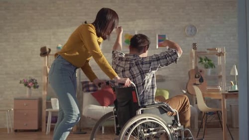 Woman Pushing Smiling Man in Wheelchair at Home