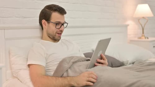 Man Using Tablet in Bed at Night