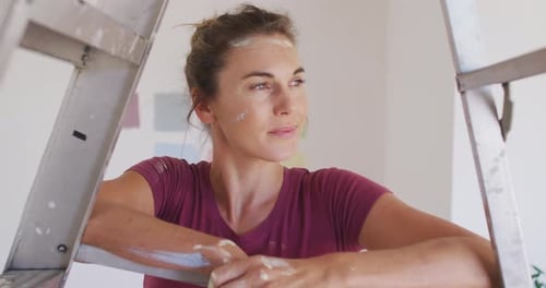 Smiling Woman Resting on Ladder after Painting