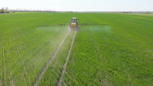 Aerial View of Farming Tractor Spraying on Field with Sprayer, Herbicides and Pesticides at Sunset
