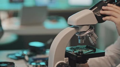 Engenheira examinando a placa de circuito sob microscópio