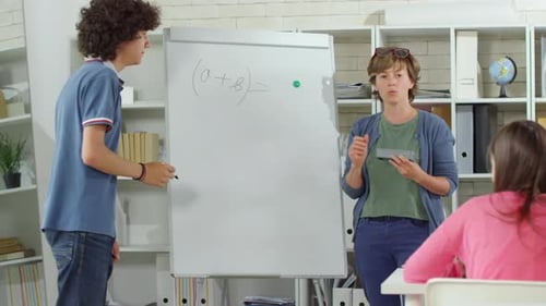 Teen Student Works Math Problem on Whiteboard
