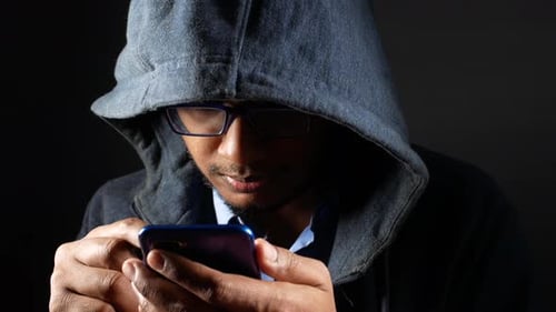 Hooded Person Using Mobile Phone in Dark Setting