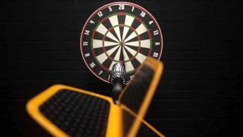 Darts arrow hitting in the bullseye of the dartboard hanging on the dark wall.
