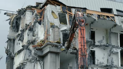 Excavator Destroys the Old Building. Demolition Work, Pieces of Concrete and Reinforcement Fall Down