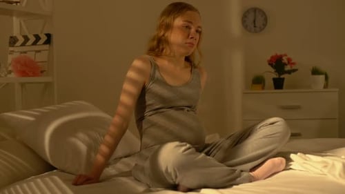 Femme désespérée en attente de toucher le ventre assise sur le lit, difficultés de grossesse