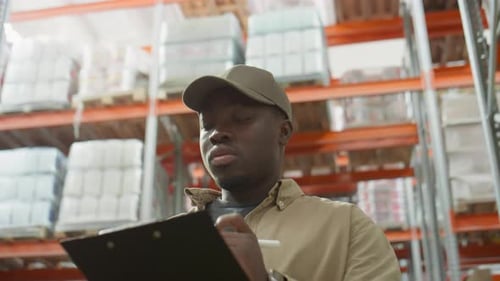 African American Warehouse Manager Taking Notes during Inventory