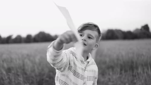 Boy Holding Paper Airplane in a Rural Field