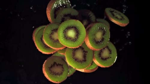 Vibrant Kiwi Slices Ascending on Black Background
