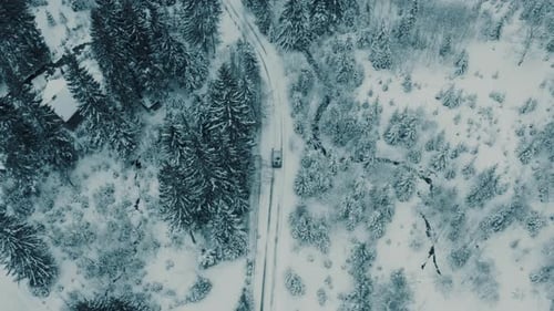 Imágenes aéreas de invierno de un pueblo de carretera sinuoso y ventoso que atraviesa un paisaje montañoso