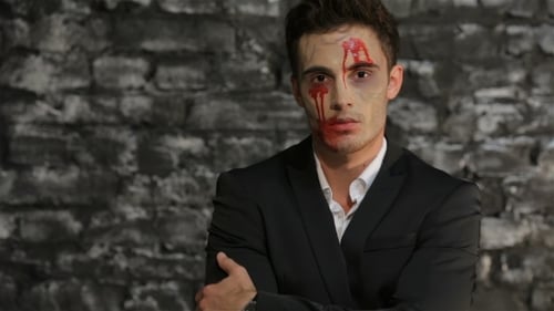 Man with pale makeup and blood on face