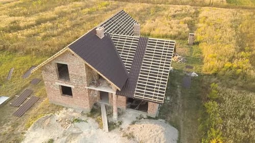 Aerial view of unfinished house with wooden roof structure covered with metal tile sheets under