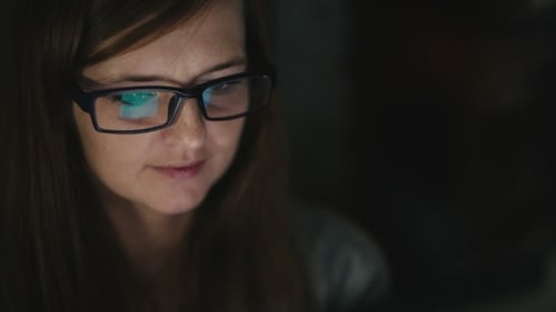 Woman Looks at Laptop Screen in Dark Room