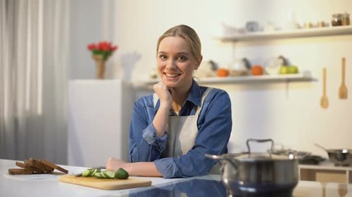 Woman Smiles in the Kitchen Near Food