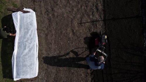 Aerial Drone View Man Farmer Working in the Garden Plows with Garden Tiller