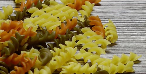 Uncooked Colorful Spiral Pasta on a Light Brown Surface