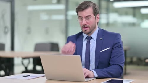 Man Coughing While Working on Laptop in Office