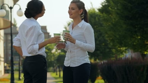 Two Women Chatting in Park, Holding Coffee