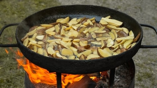 Potatoes Cooking Over Open Fire in Skillet Outdoors