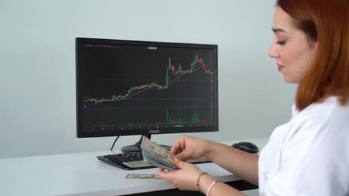Woman Analyzes Stock Data at Desk, Counts Money