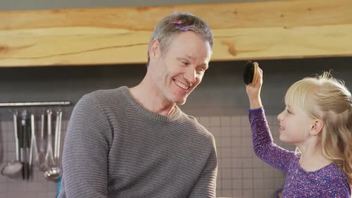 Adorable Girl Styling Father's Hair in Kitchen