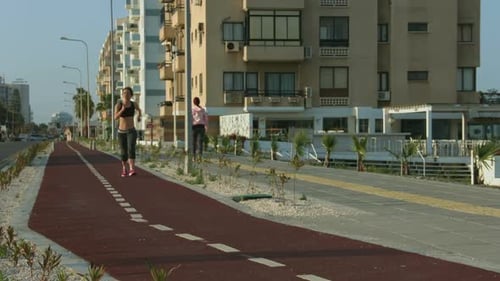 Happy Young Woman Jogging With Smile on Face, Enjoying Sunny Morning in City