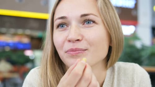 Young Woman Eating French Fries with Sauce Close Up
