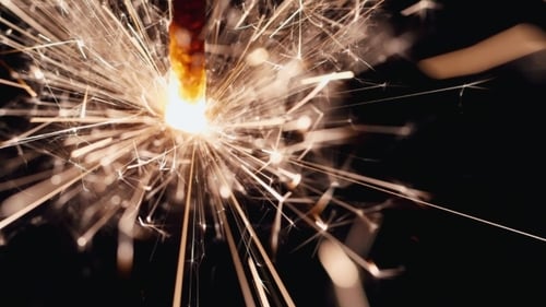 Burning Sparkler Emitting Bright Colorful Sparks on Black