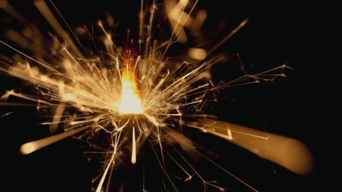 Sparkling Sparkler Emitting Golden Sparks Against Black Background