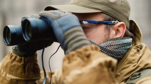 Man Wearing Cap Uses Binoculars in Nature