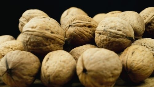 Pile of Textured Walnuts on Wooden Surface