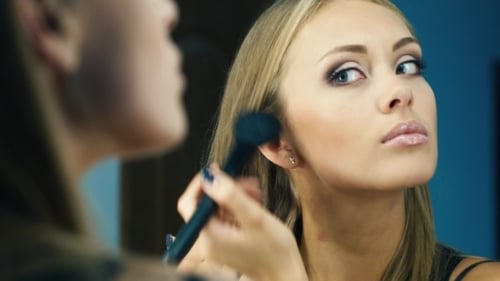 Woman Applying Makeup in Front of Mirror