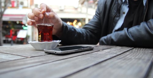 Person Using Phone with Tea Outdoors