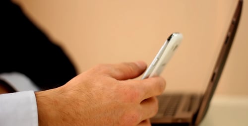 Hands Using Cellphone and Laptop at Desk