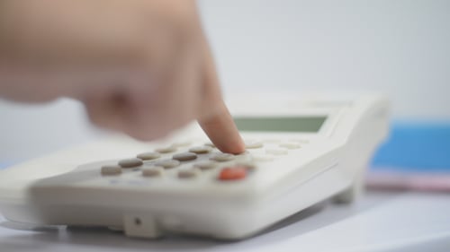 Hand Dials Number on White Landline Telephone
