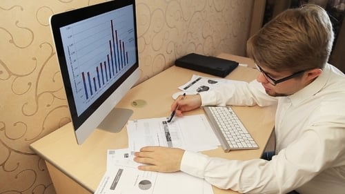 Man Working at Desk With Computer and Charts