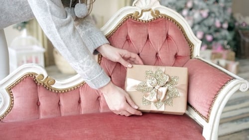 Woman Places Gift on Ornate Pink Chaise Lounge