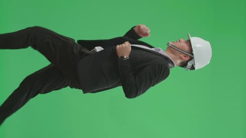 Side View Of Asian Chief Engineer In The Hard Hat Runs On Green Screen Chroma Key