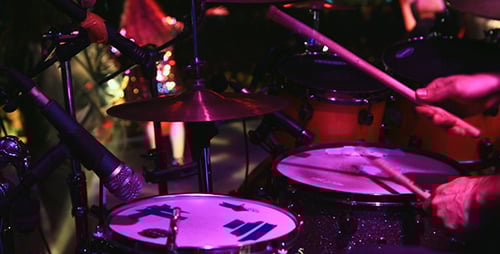 Drummer Playing Energetically at Nighttime Concert