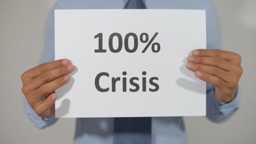 Person Holds Sign Stating One Hundred Percent Crisis