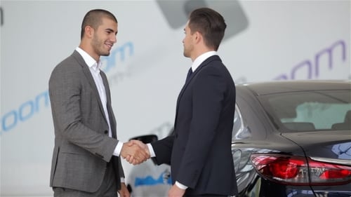 Men in Suits Shake Hands Near Car