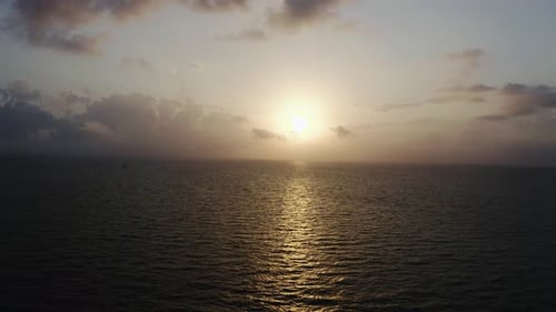 Vista aérea Zumbido de nubes coloridas y brillantes durante la puesta de sol sobre el mar o el océano