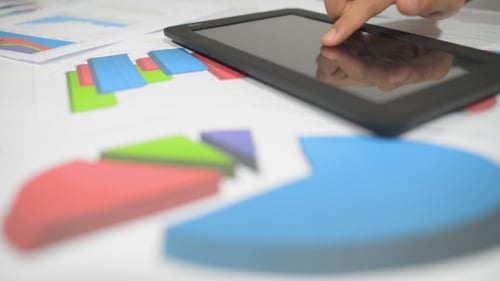 Fingertip Touches Tablet Displayed Over Charts