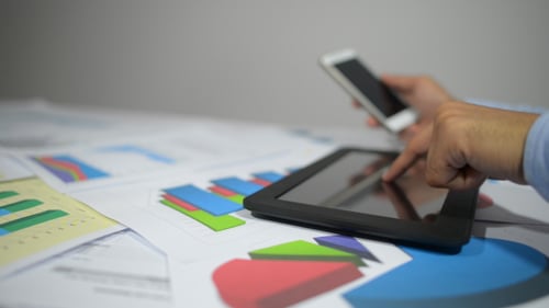 Hands Using Tablet and Smartphone with Charts
