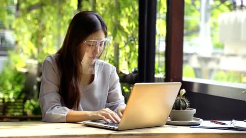Woman Working on Laptop with Face Shield