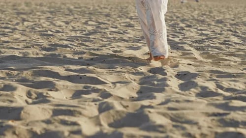 Legs of Girl Wearing White Long Dress Walking Barefoot Sand on Sea Beach or Desert. Slow Motion