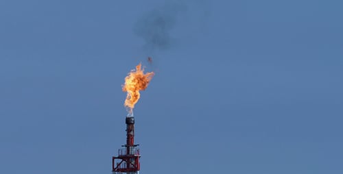 Industrial Tower Burning Flame Against Blue Sky