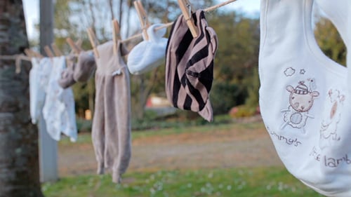 Baby Clothes Drying on Clothesline in Grassy Field