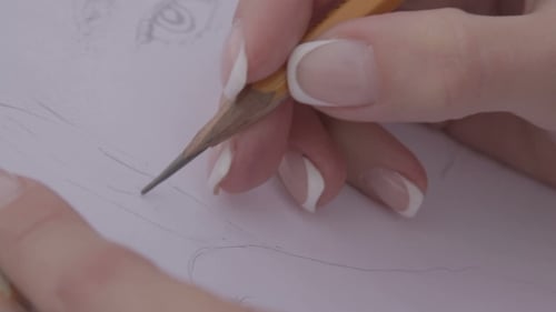 Close Up of Hands Sketching Portrait on Paper