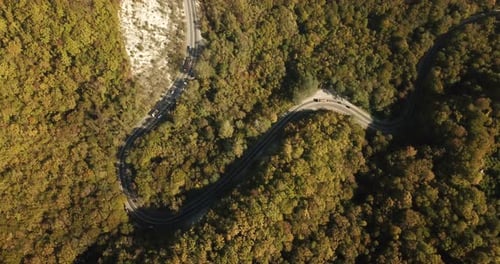 Aerial View of Car Driving Along The Winding Mountain Pass Road Through The Forest Trees. Autumn